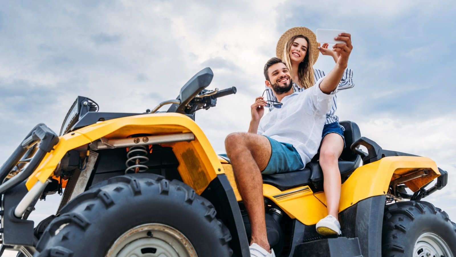 happy young couple sitting on atv and taking selfie e1645648008790 Mallku Expediciones